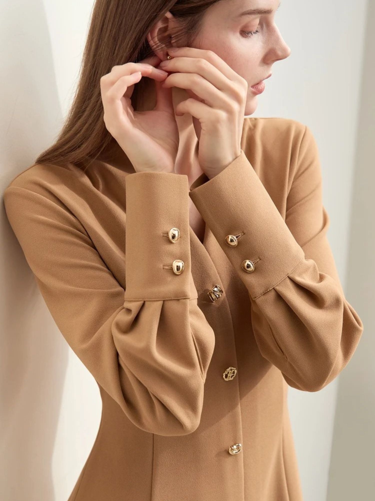 Model adjusting collar of camel v-neck midi dress with soft texture