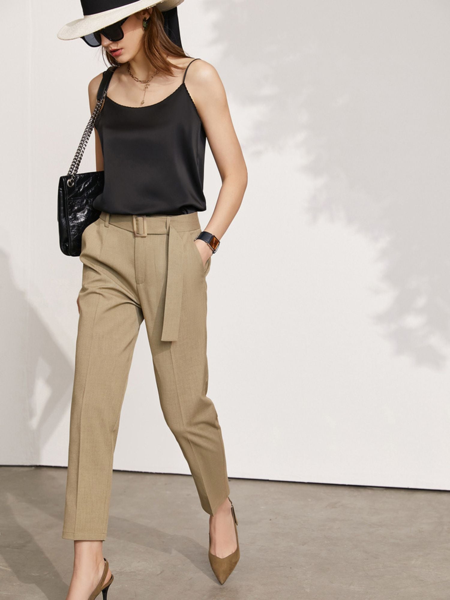 Frau trägt schwarzes Satintop mit Blazer und beigefarbener Hose, frontal aufgenommen

