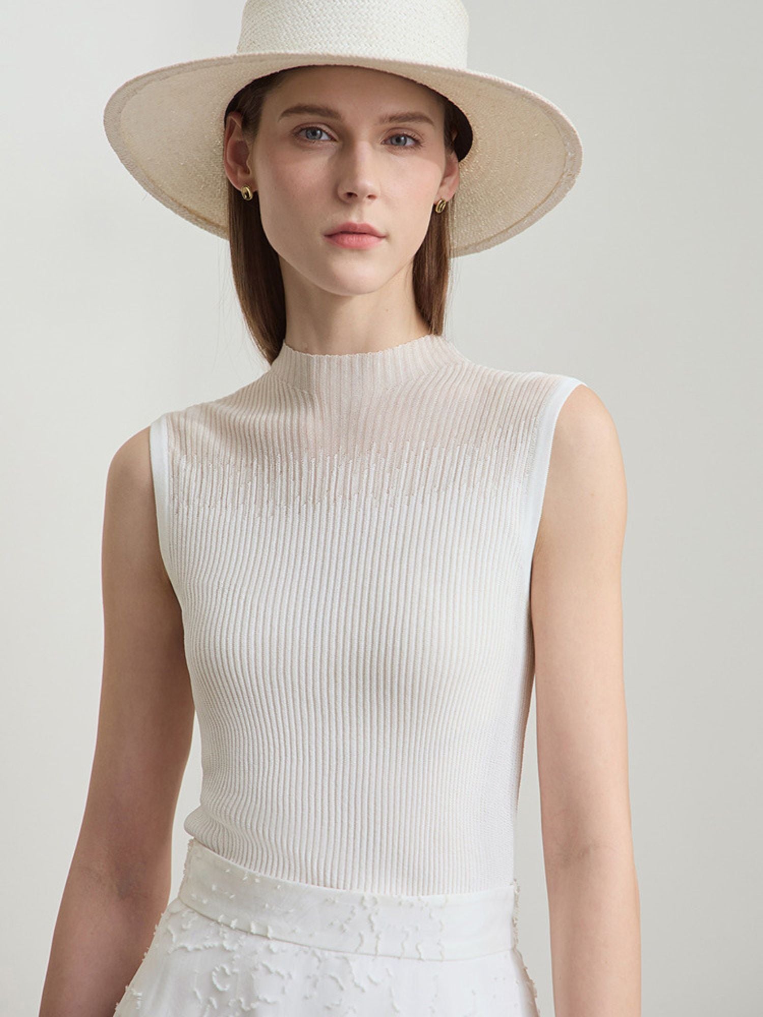 Frau mit ärmellosem cremefarbenem Top und weißem Rock, frontal aufgenommen