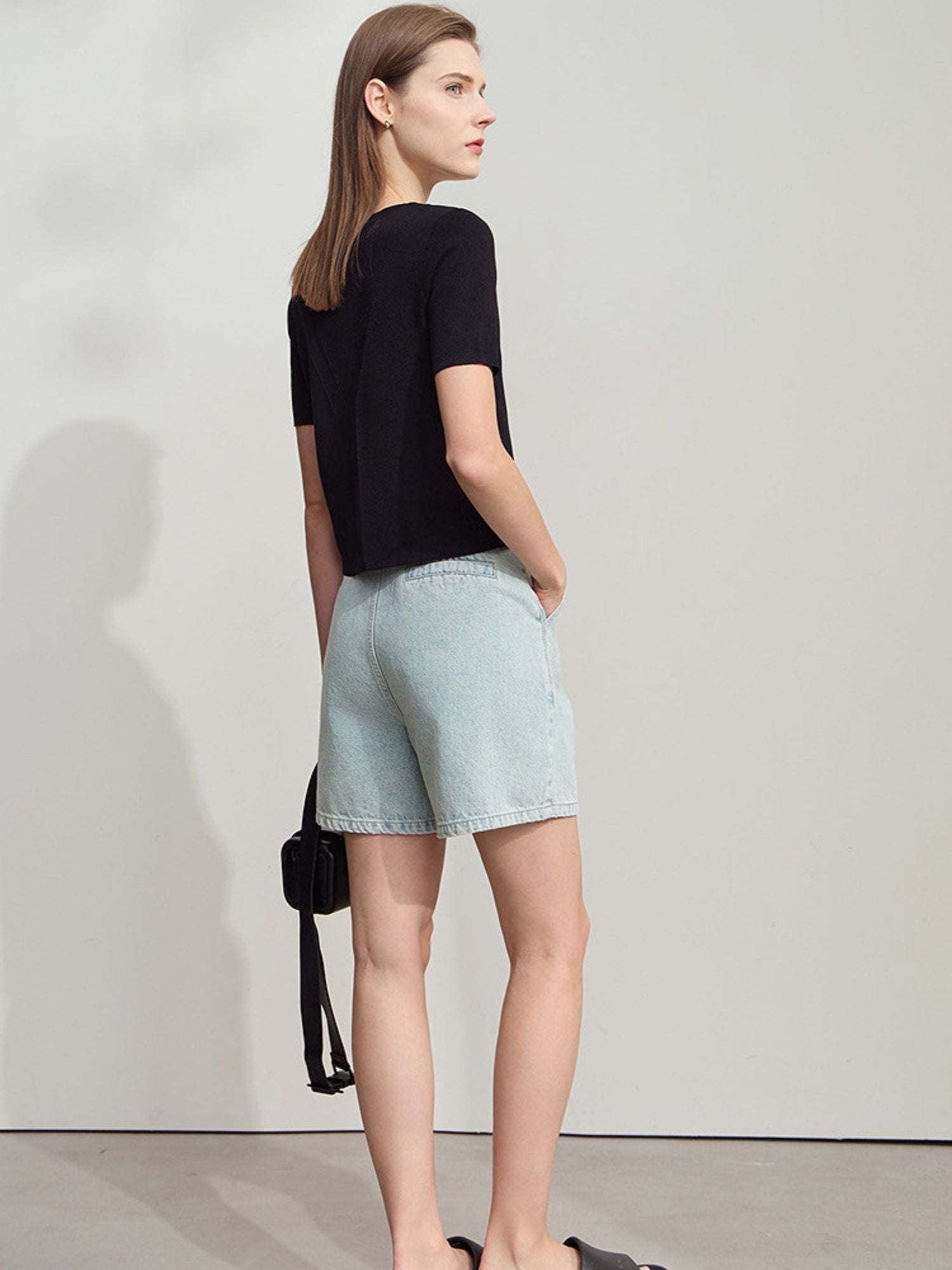 Frau trägt weißes Top mit kurzen Ärmeln und mintgrüner Hose, entspannt stehend