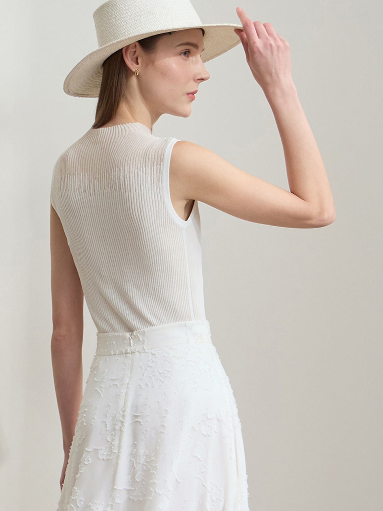 Frau in cremefarbenem Outfit mit Rippenstruktur, fotografiert von hinten