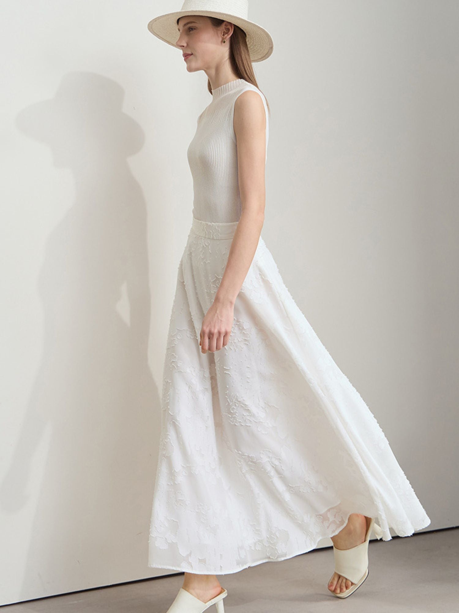 Schwungvolle Seitenansicht der Frau im weißen Rock mit ärmellosem Top und Sonnenhut