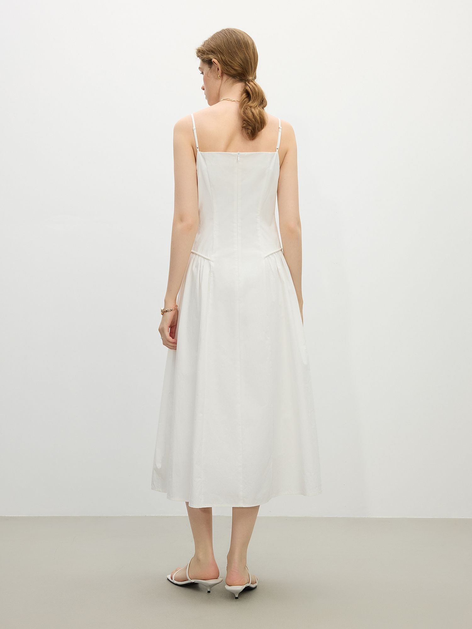 Weißes Sommerkleid mit Trägern, V-Ausschnitt und luftigem Faltenwurf, kombiniert mit Korbtasche