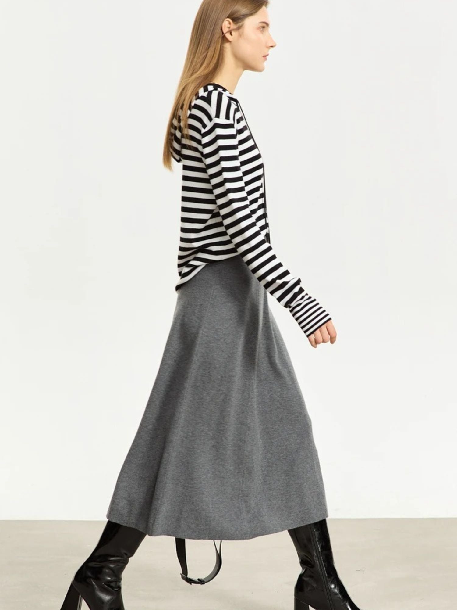 Side view of grey A-line midi skirt with soft drape, styled with striped top and black boots