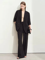 Black oversized blazer with wide-leg trousers, styled with beige top and heeled sandals

