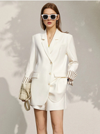 White tailored blazer and shorts set with striped cuff detail, styled with sunglasses and cream clutch
