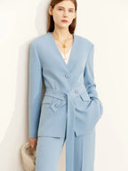 Front view of tailored light blue pantsuit with belted blazer and flap pockets