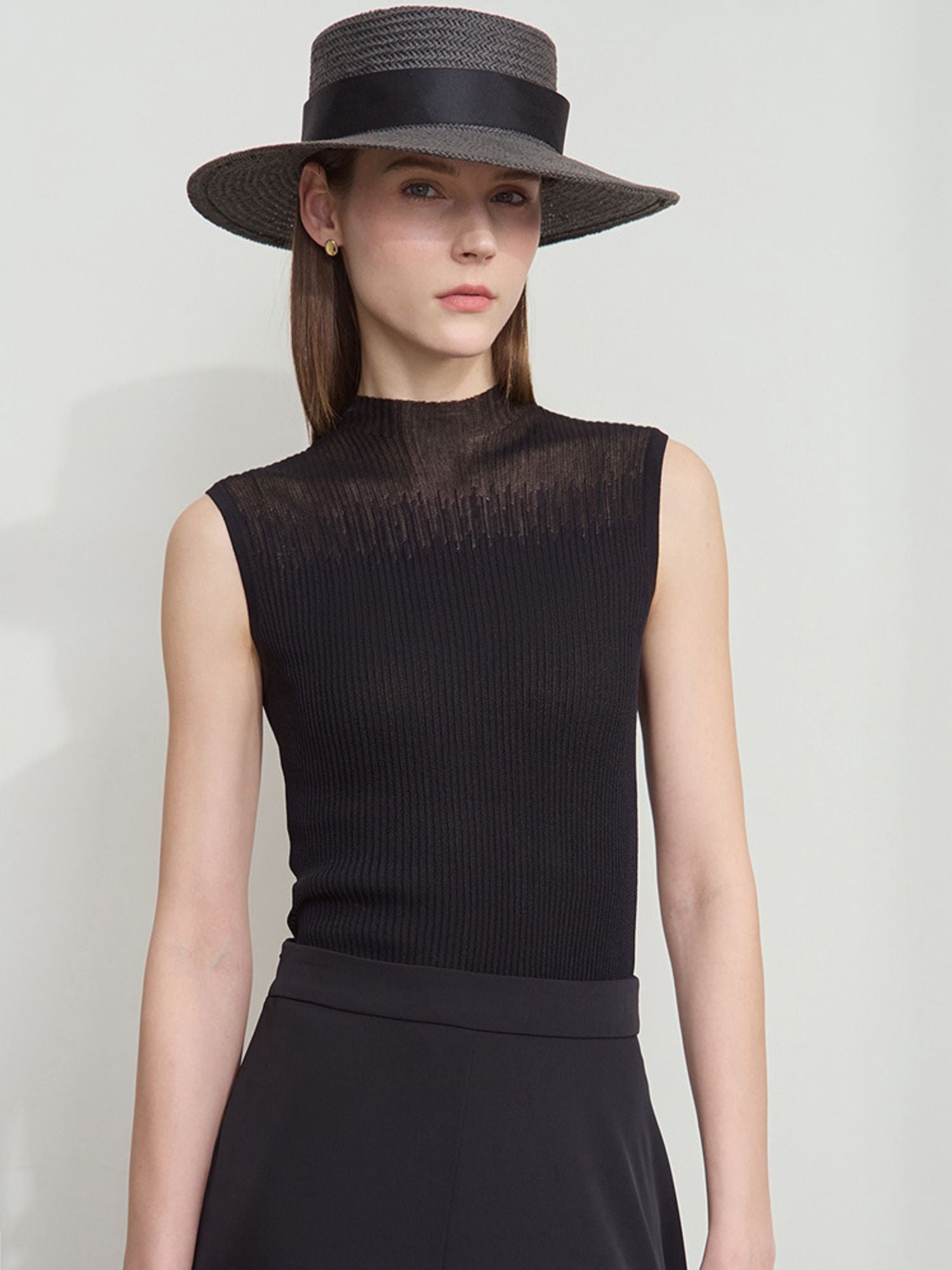 Frau mit schwarzem Top, weitem schwarzen Rock und schwarzem Hut, frontal fotografiert