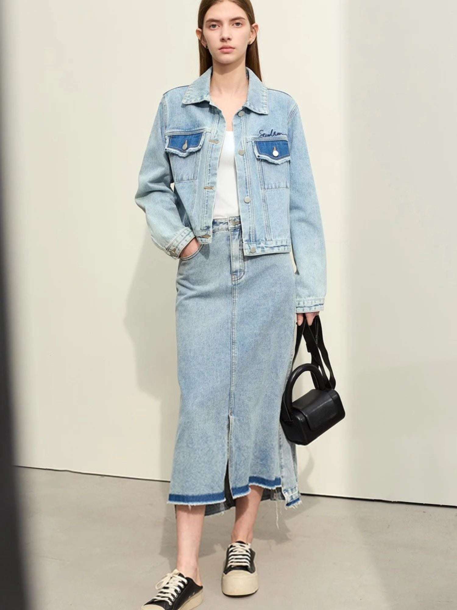 Front view of denim midi skirt paired with oversized denim jacket and sneakers