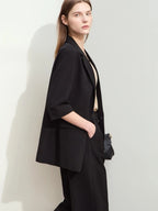 Side view of loose-fit black suit with three-quarter sleeve blazer and relaxed pants