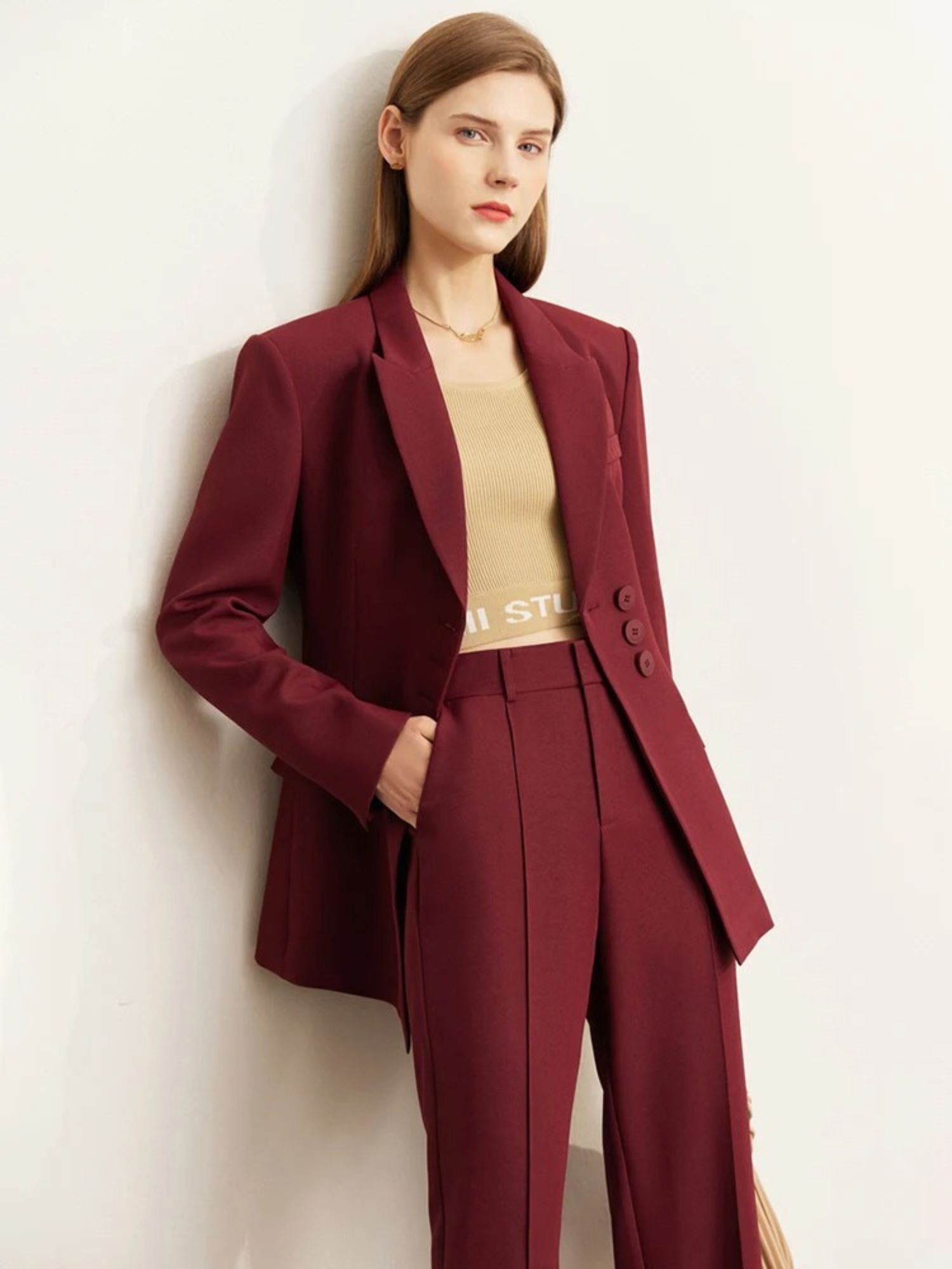 Side angle of burgundy pantsuit with peak lapel blazer and structured fit