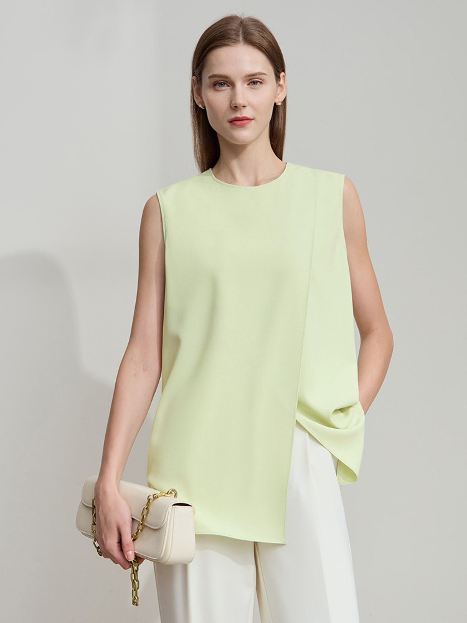 Frau in hellgrüner ärmelloser Bluse mit geschwungenem Saum, von vorne fotografiert