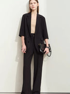 Front view of flowy black pantsuit with soft tailoring, worn with minimal accessories