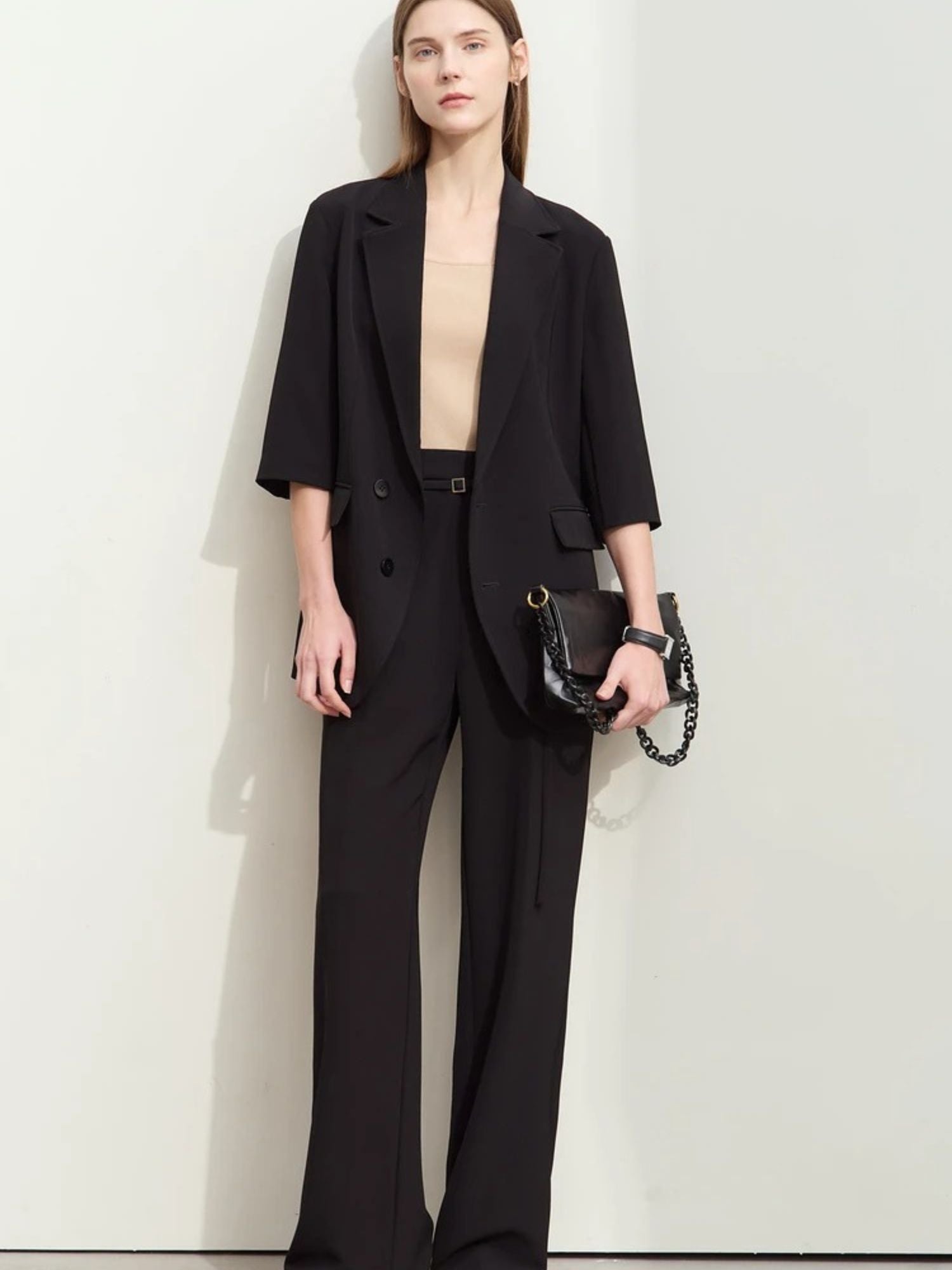 Front view of flowy black pantsuit with soft tailoring, worn with minimal accessories