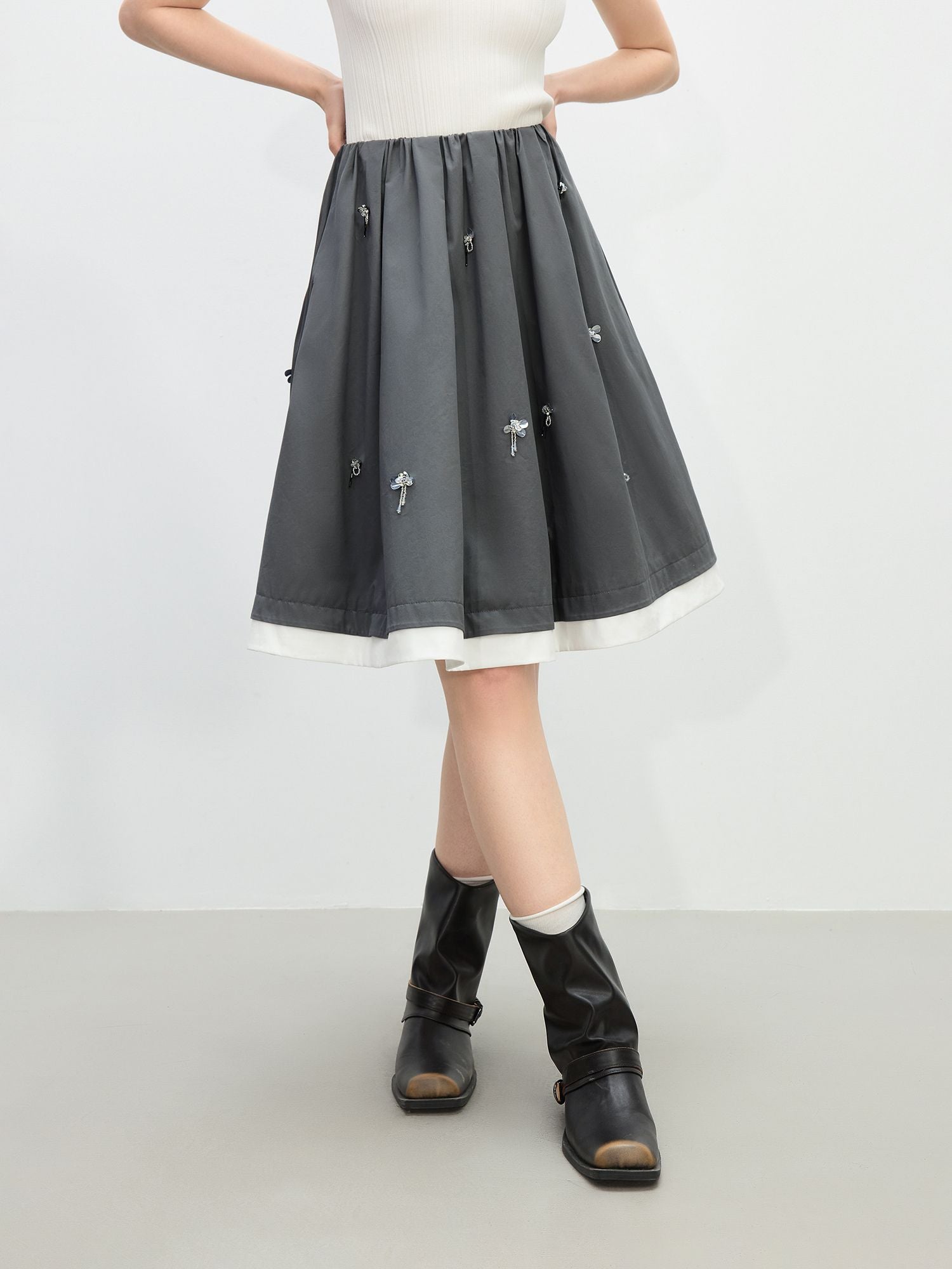 Vorderansicht des grauen Rocks mit floralen Stickdetails und leichter A-Linie