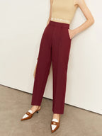 High-waisted burgundy trousers styled with sleeveless beige top and heels