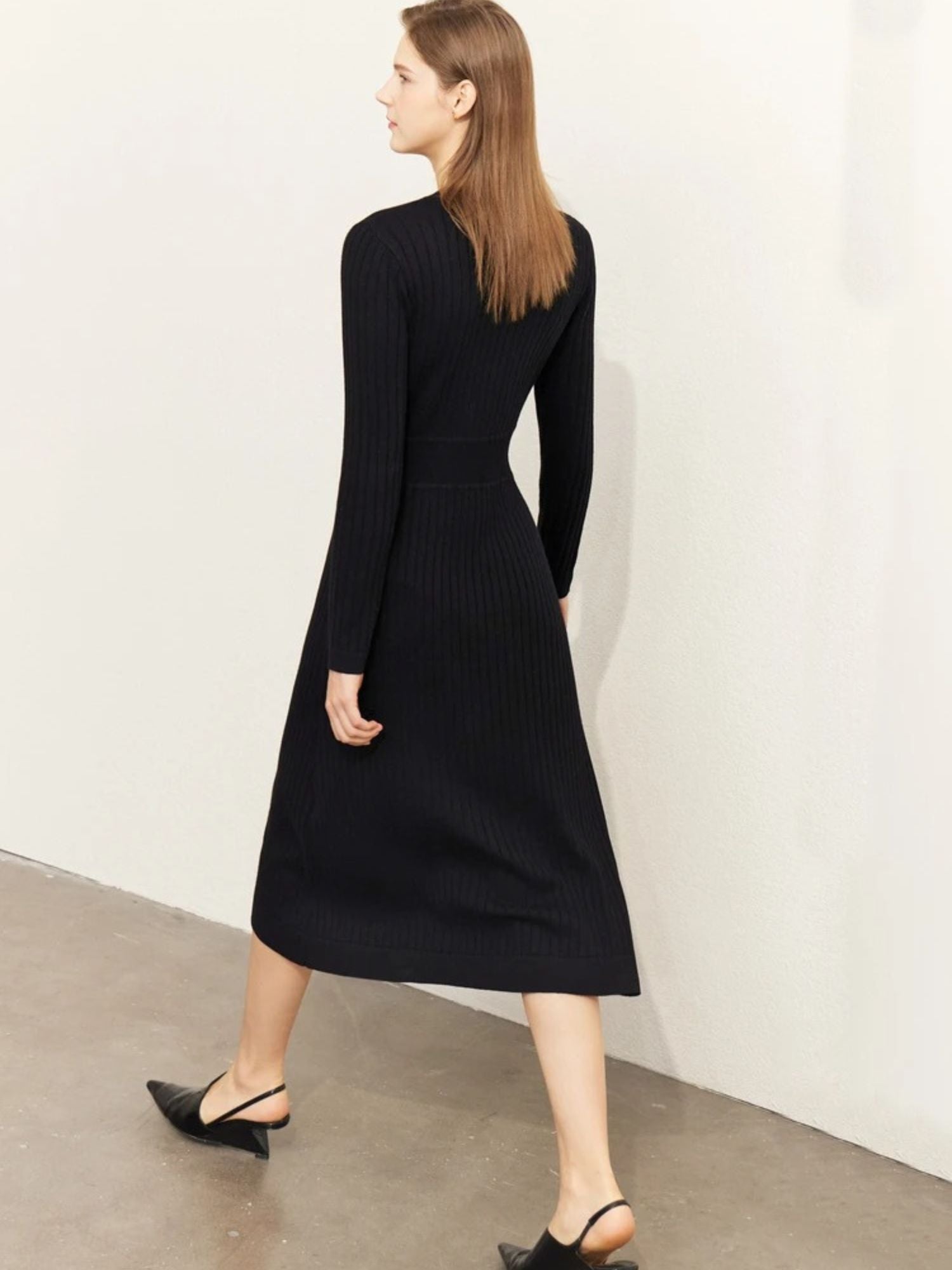 Back view of black ribbed midi dress with flared hem and structured shape