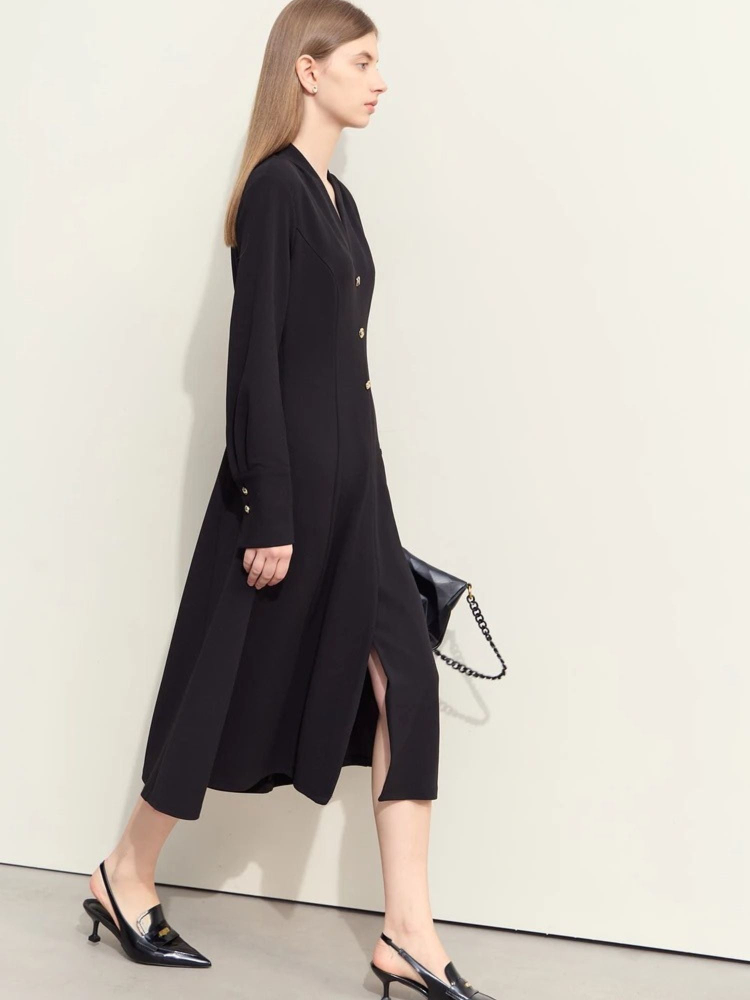 Side view of black button-front dress with midi hem and minimal accessories

