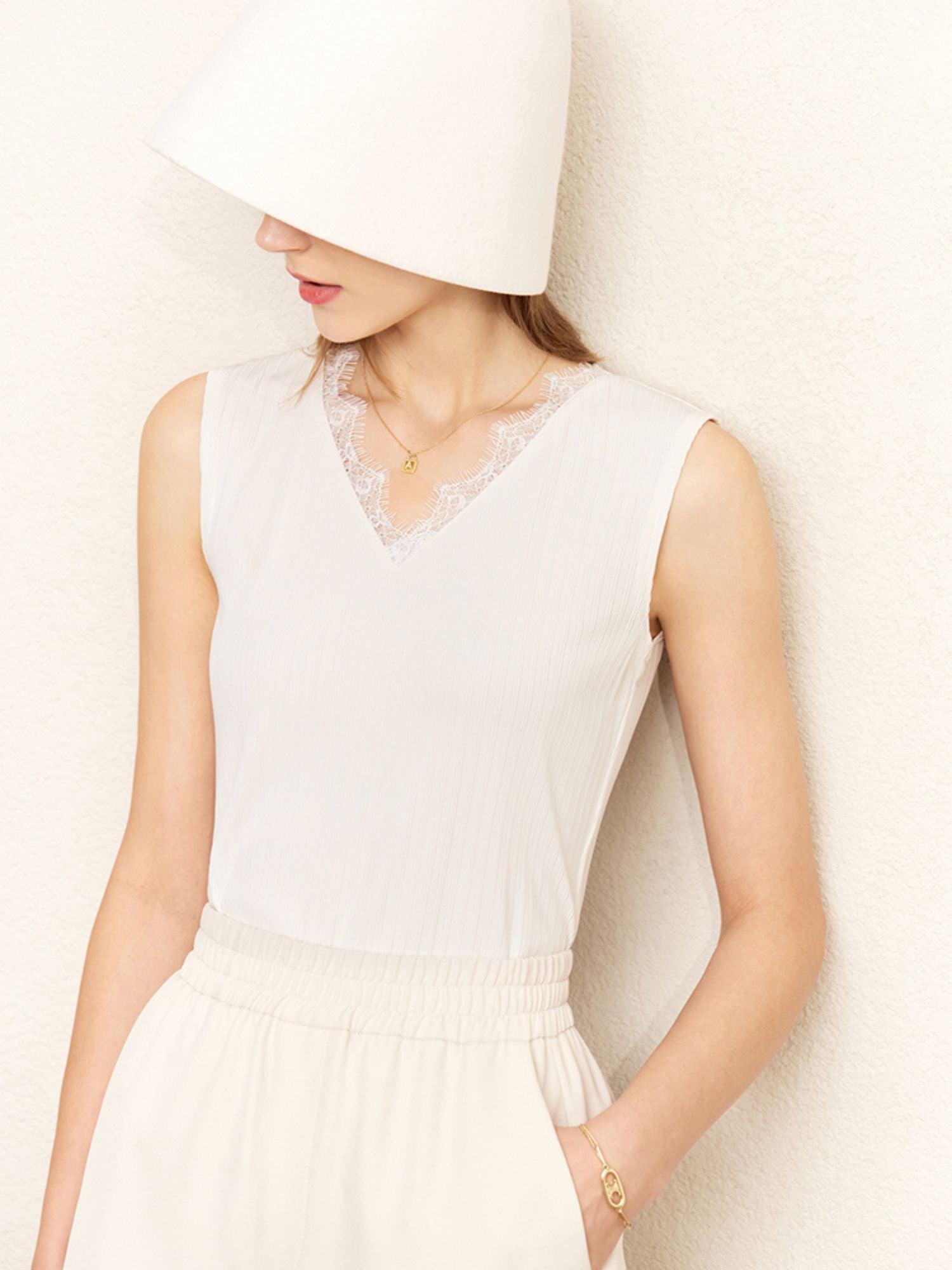 Frau mit Eimerhut trägt weißes ärmelloses Top mit eleganter Spitze