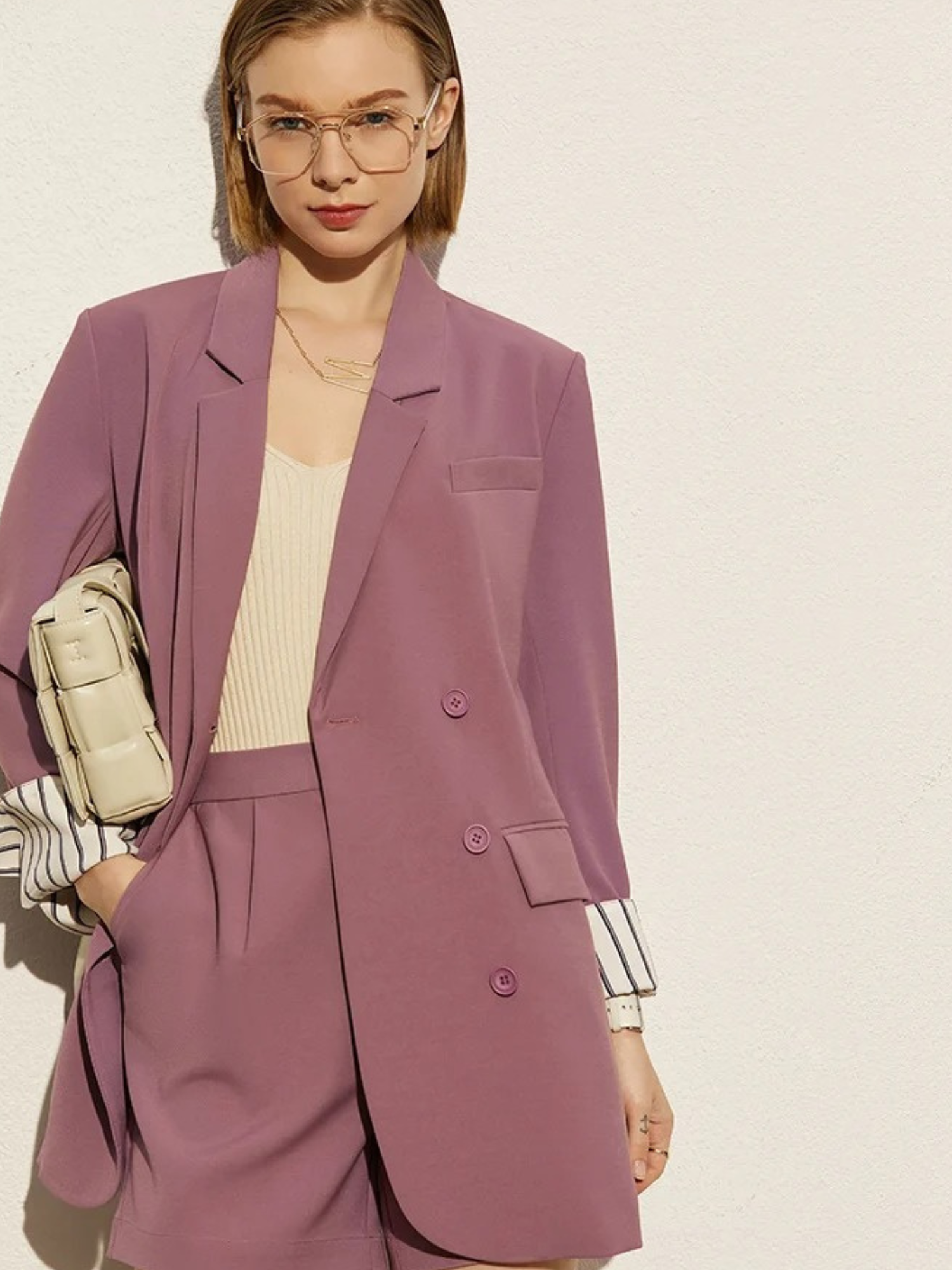Front view of dusty rose blazer and shorts with striped cuff detail and beige handbag