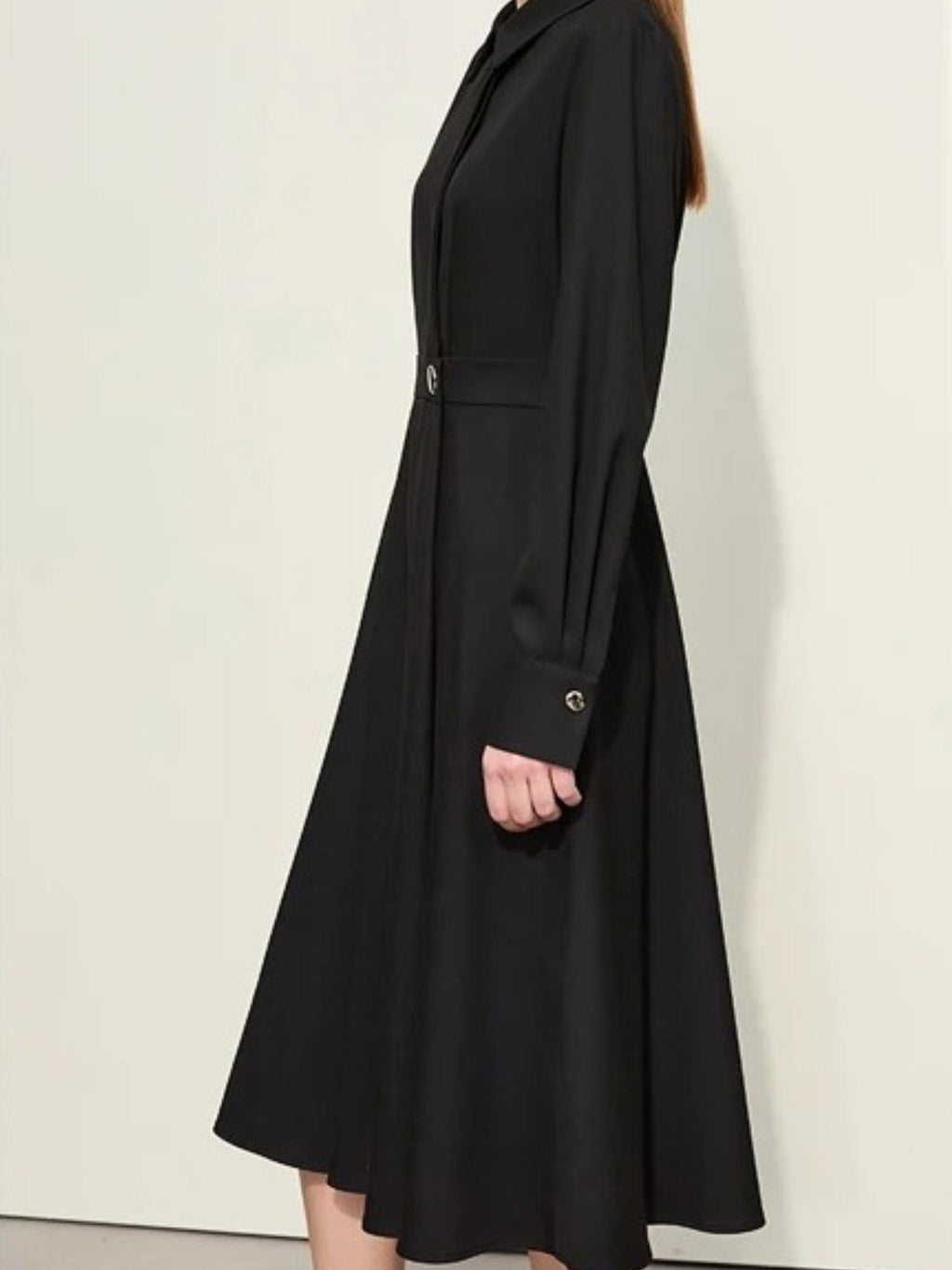 Angled back view of black buttoned dress with pleated skirt and midi length