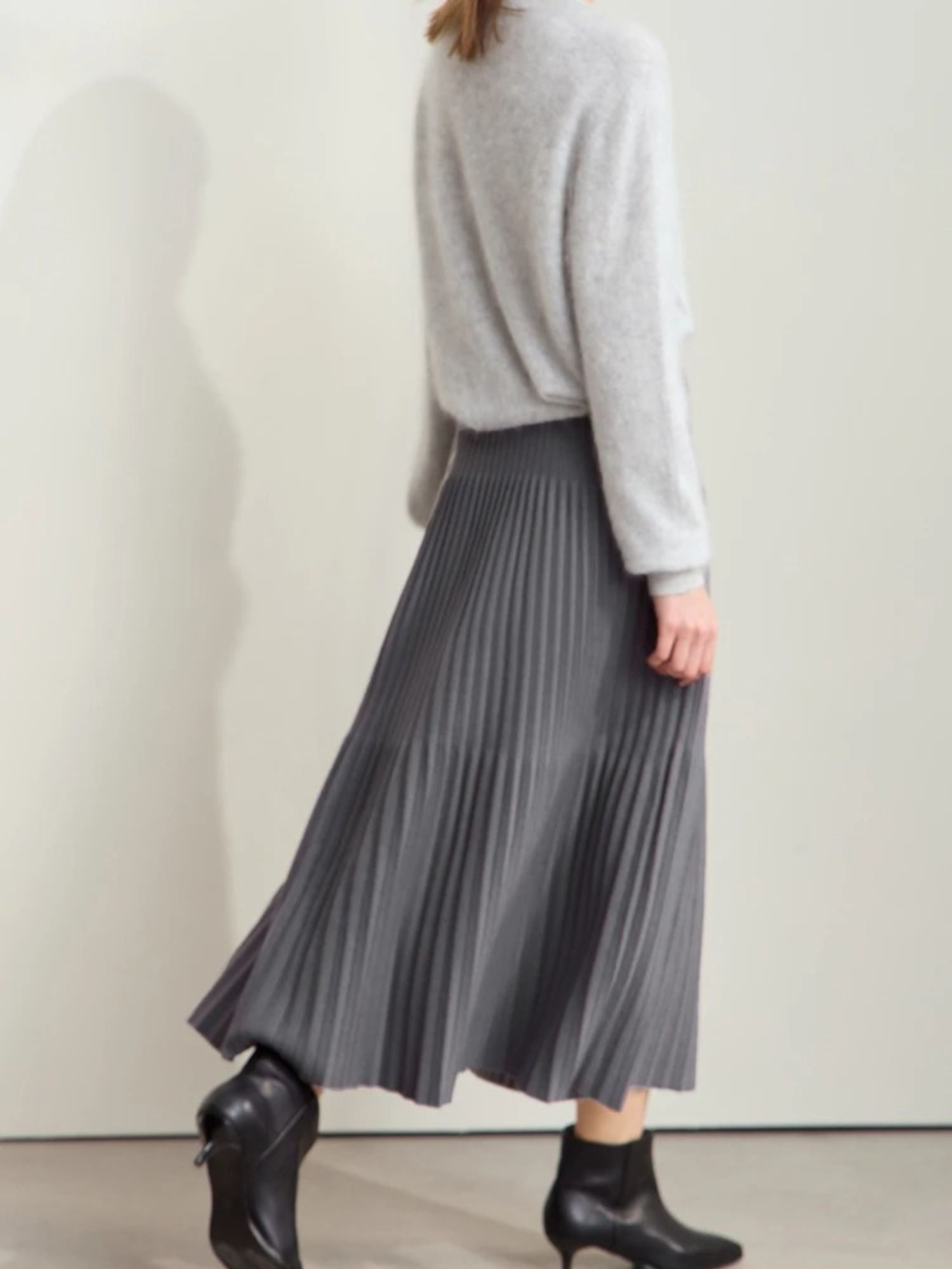 Back view of pleated grey midi skirt with light and dark panels, paired with black shoes