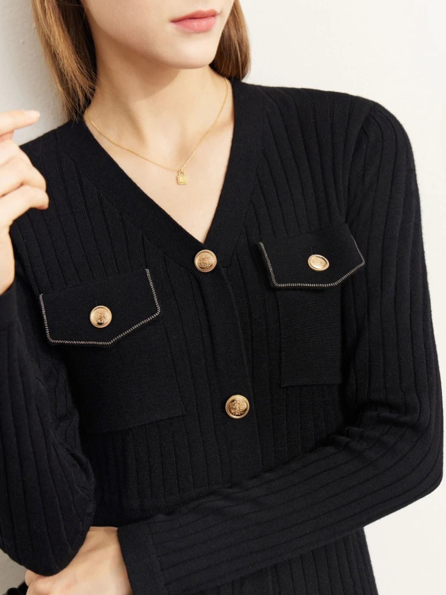 Close-up of chest pocket and gold button detail on black ribbed dress
