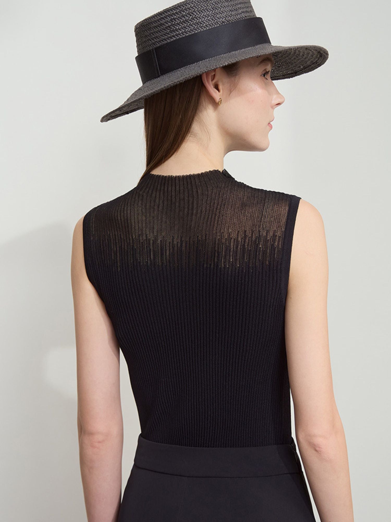 Frau trägt schwarzes ärmelloses Top mit weitem Rock und schwarzem Hut, ganzkörper Ansicht