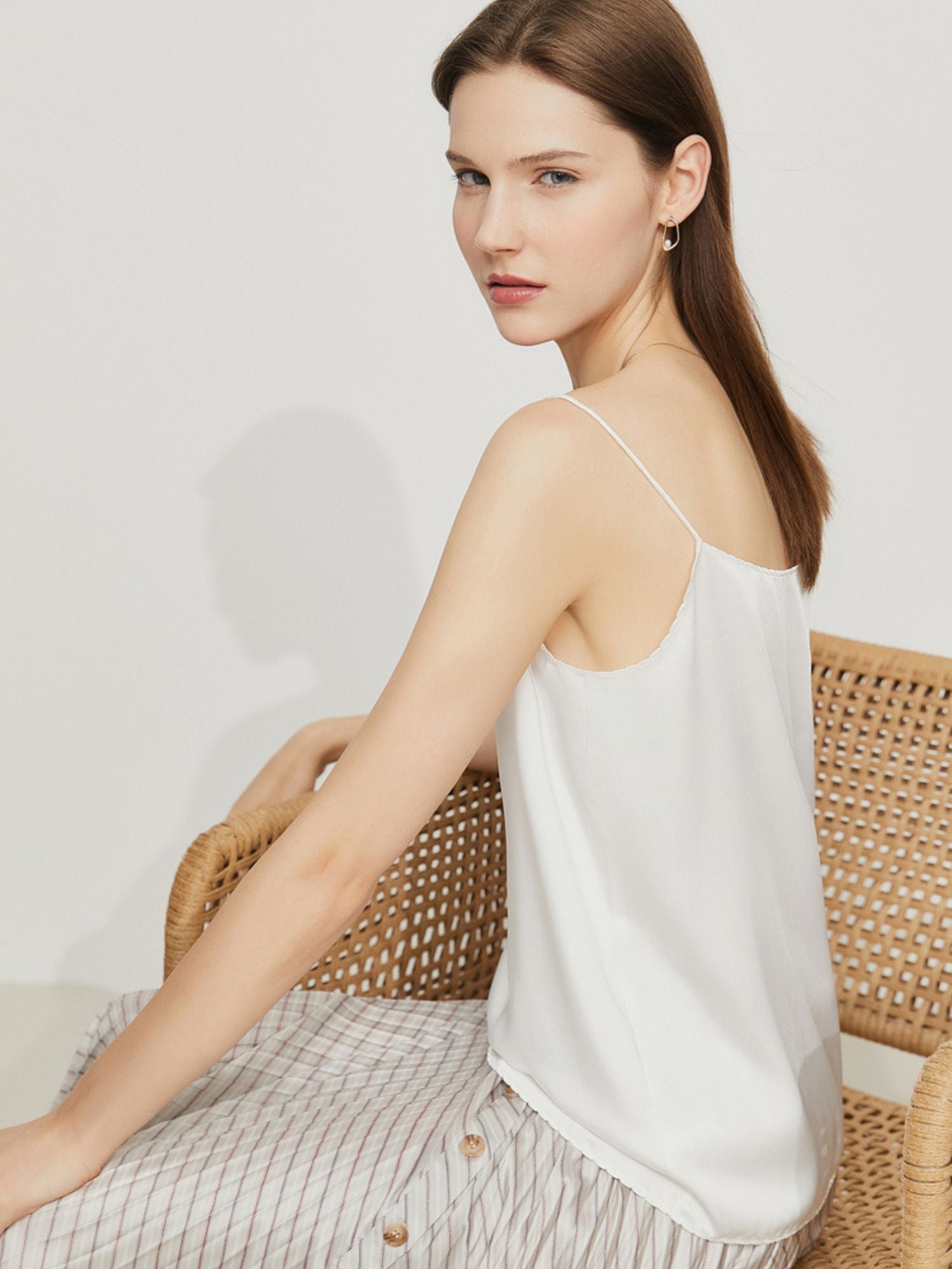 Frau geht in weißem Top und schwingendem karierten Rock

