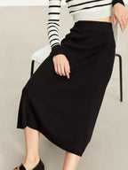 Model sitting in high-waisted black ribbed skirt with flared hem