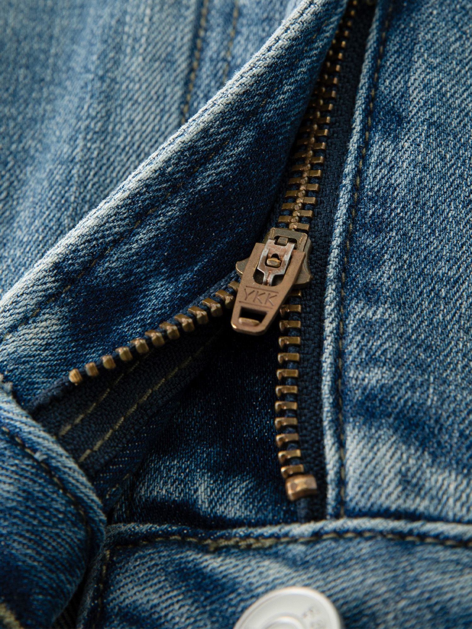 Detailaufnahme des Knopfverschlusses und Bunds der blauen Jeans