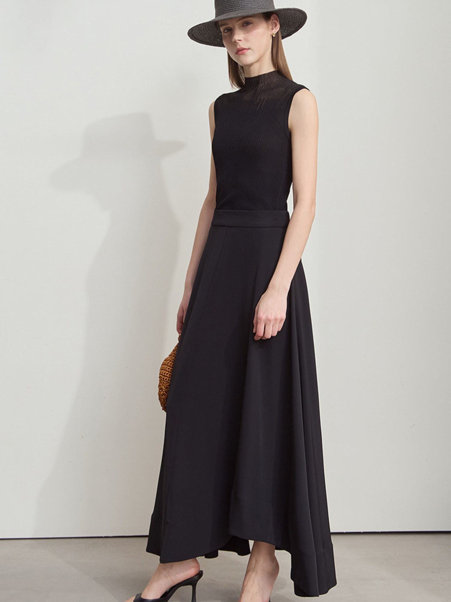 Frau in blauem Top mit weißem Rock, leicht zur Seite gewendet, mit Tasche