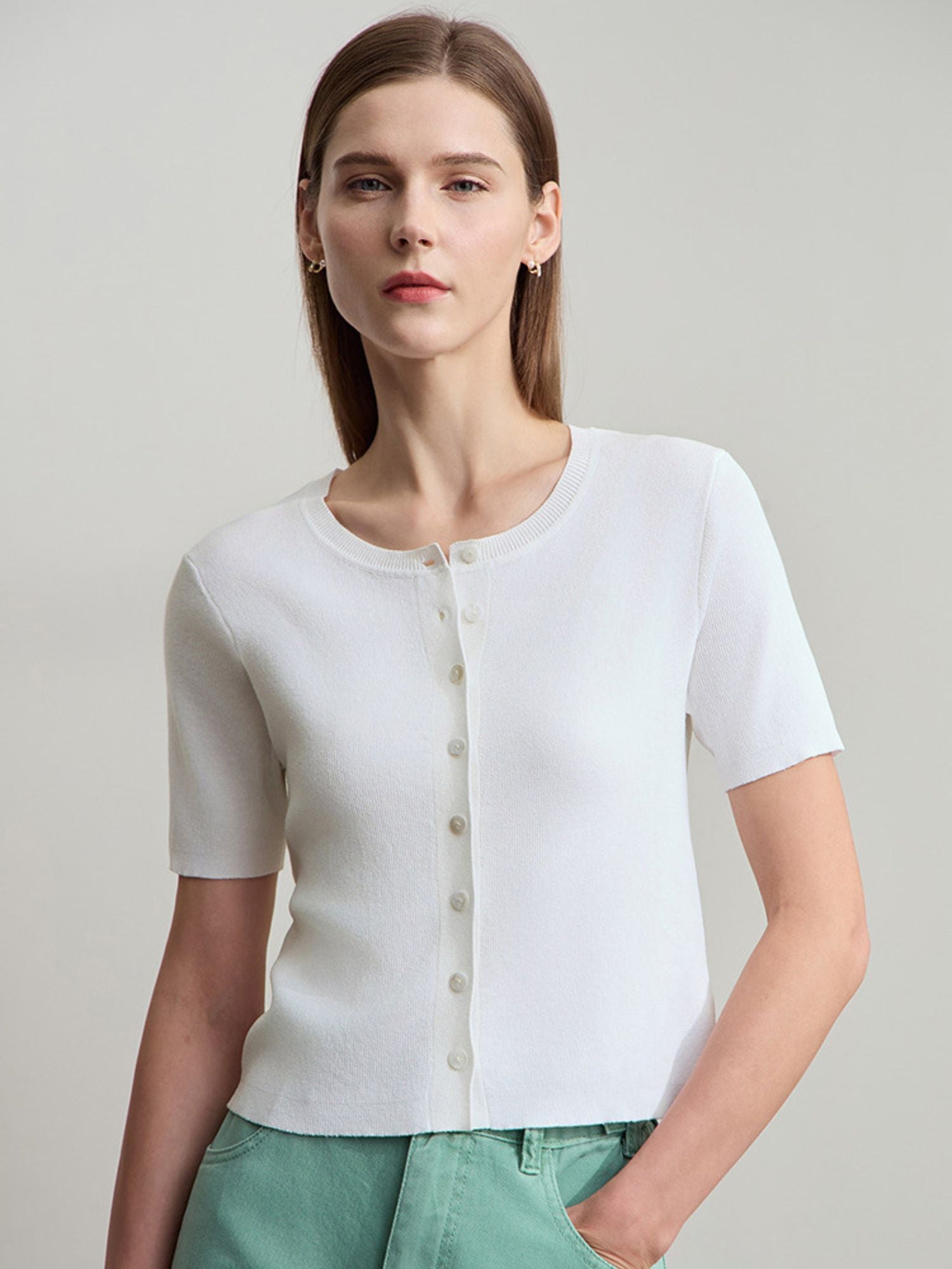 Weißes Stricktop mit kurzen Ärmeln, Knopfleiste und mintgrüner Hose, frontal fotografiert