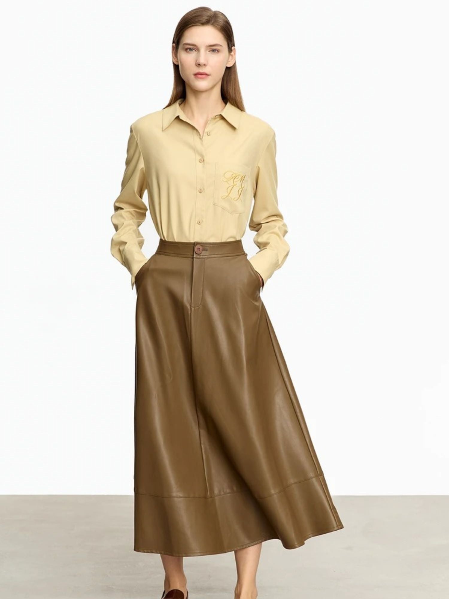 Front view of brown A-line midi skirt styled with beige button-down shirt