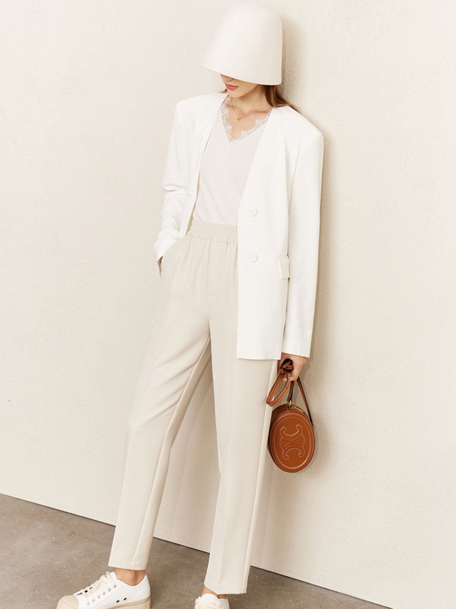 Frau mit Eimerhut in weißem Outfit mit ärmellosem Spitzen-Top