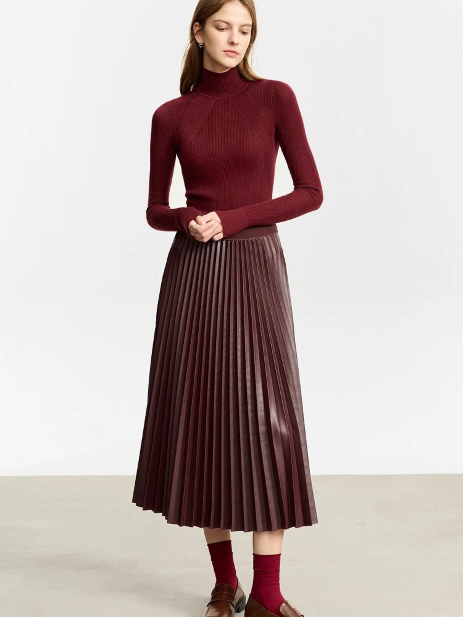 Front view of burgundy pleated midi skirt styled with red ankle boots and matching top