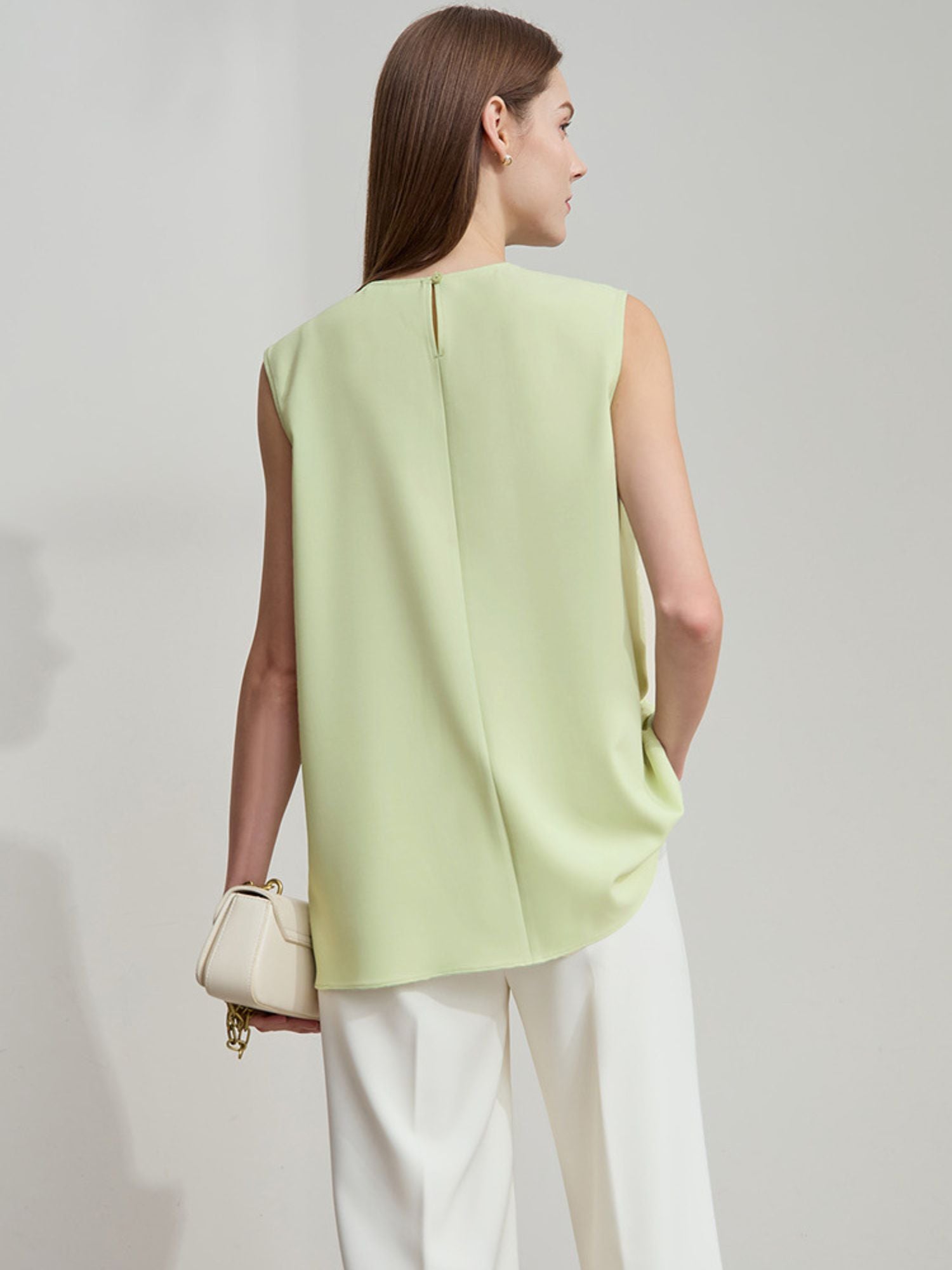 Frau trägt hellgrüne Bluse mit asymmetrischem Design, leichte Seitenansicht