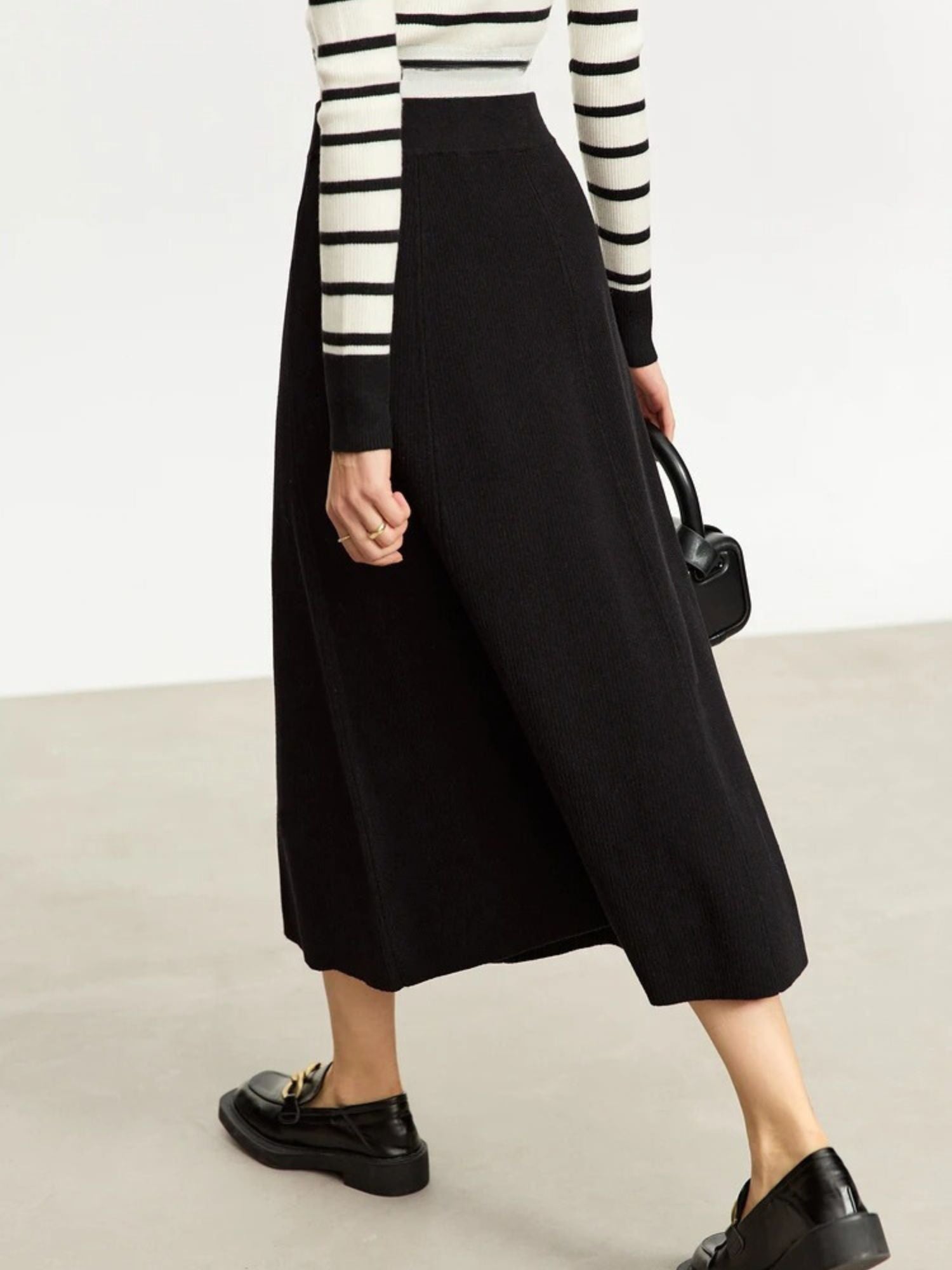 Front view of black midi skirt styled with striped long-sleeve top and loafers