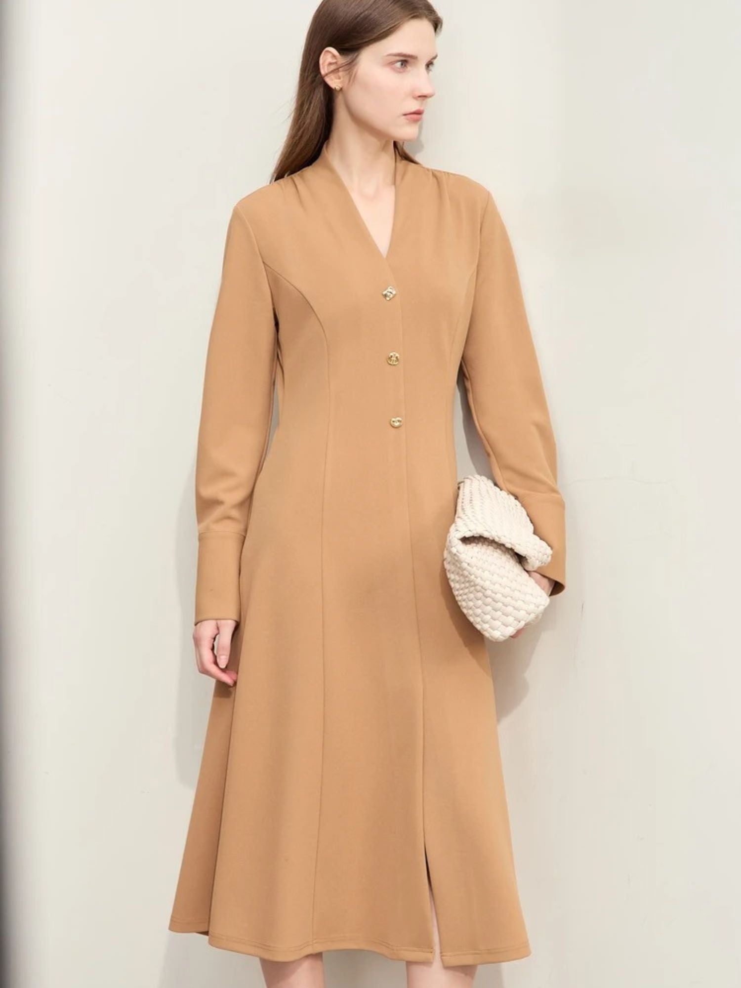 Side view of camel button-down dress styled with cream handbag