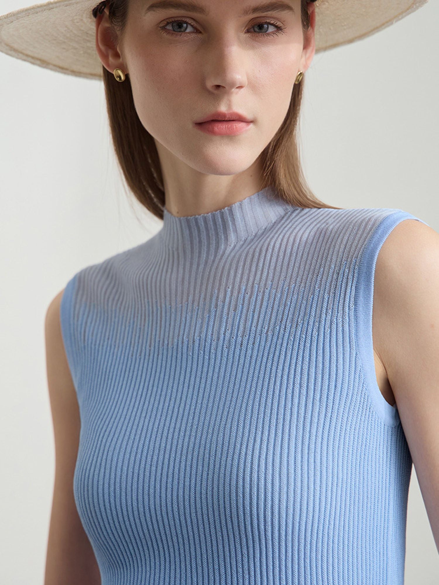 Frau in blauem Top mit weißer Hose, frontal mit breitem Sonnenhut