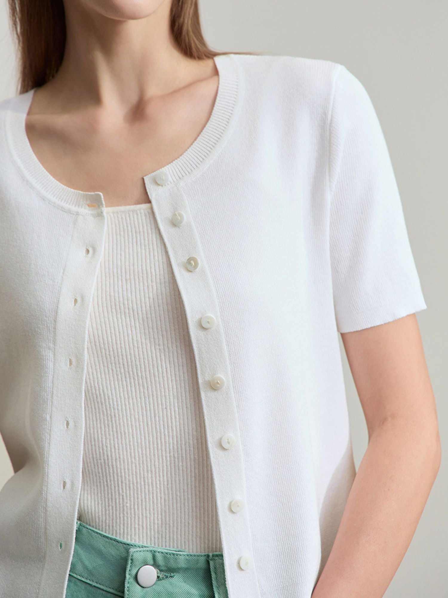 Frau trägt weißes Top mit kurzen Ärmeln, leicht zur Seite gewendet