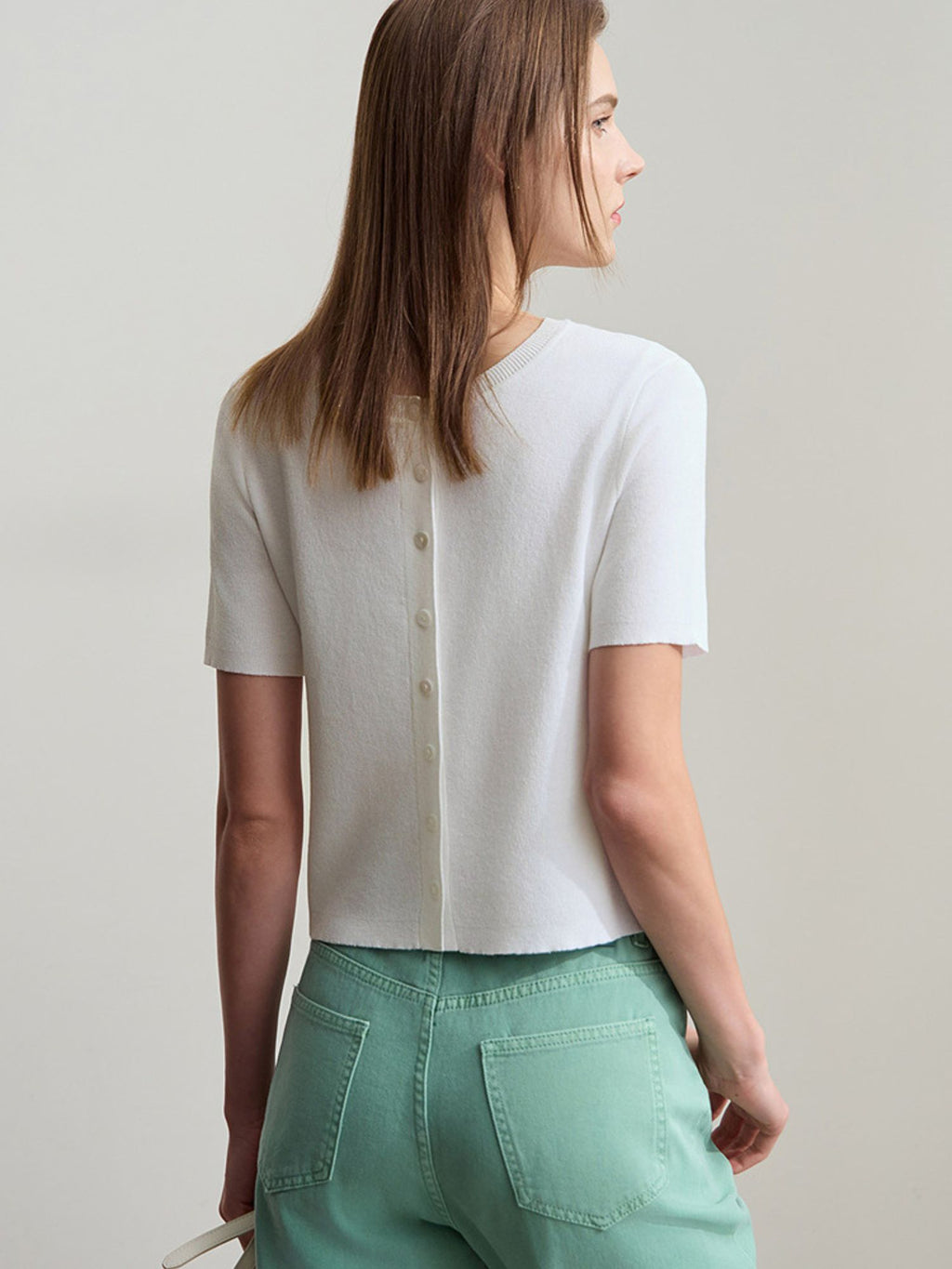 Weißes Stricktop mit kurzen Ärmeln und mintgrüner Hose, freistehend