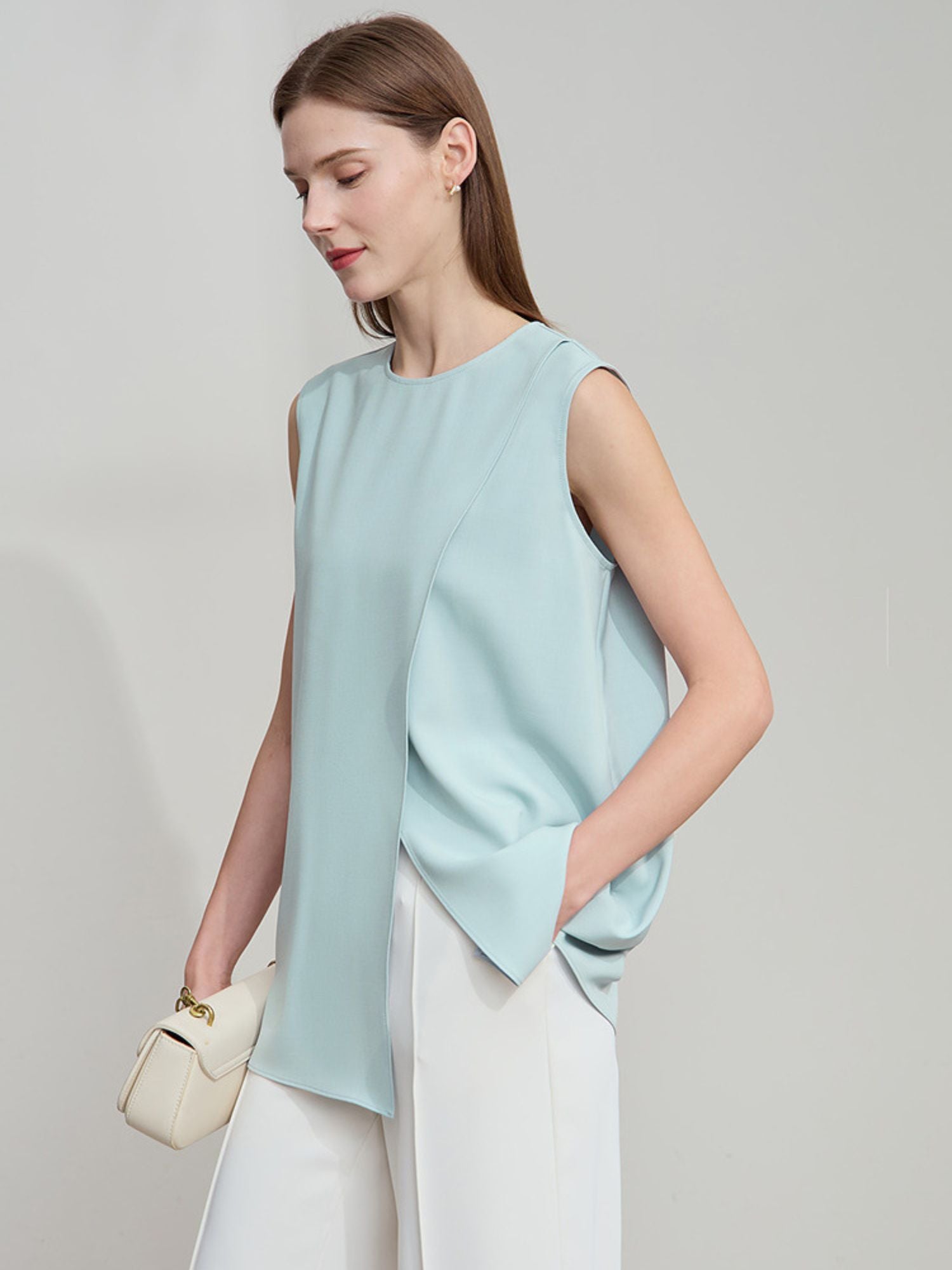 Frau lächelt und trägt blaue ärmellose Bluse mit seitlicher Falte