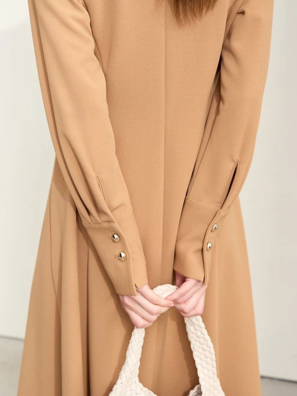 Close-up of camel dress sleeves with gold buttons and gathered cuffs