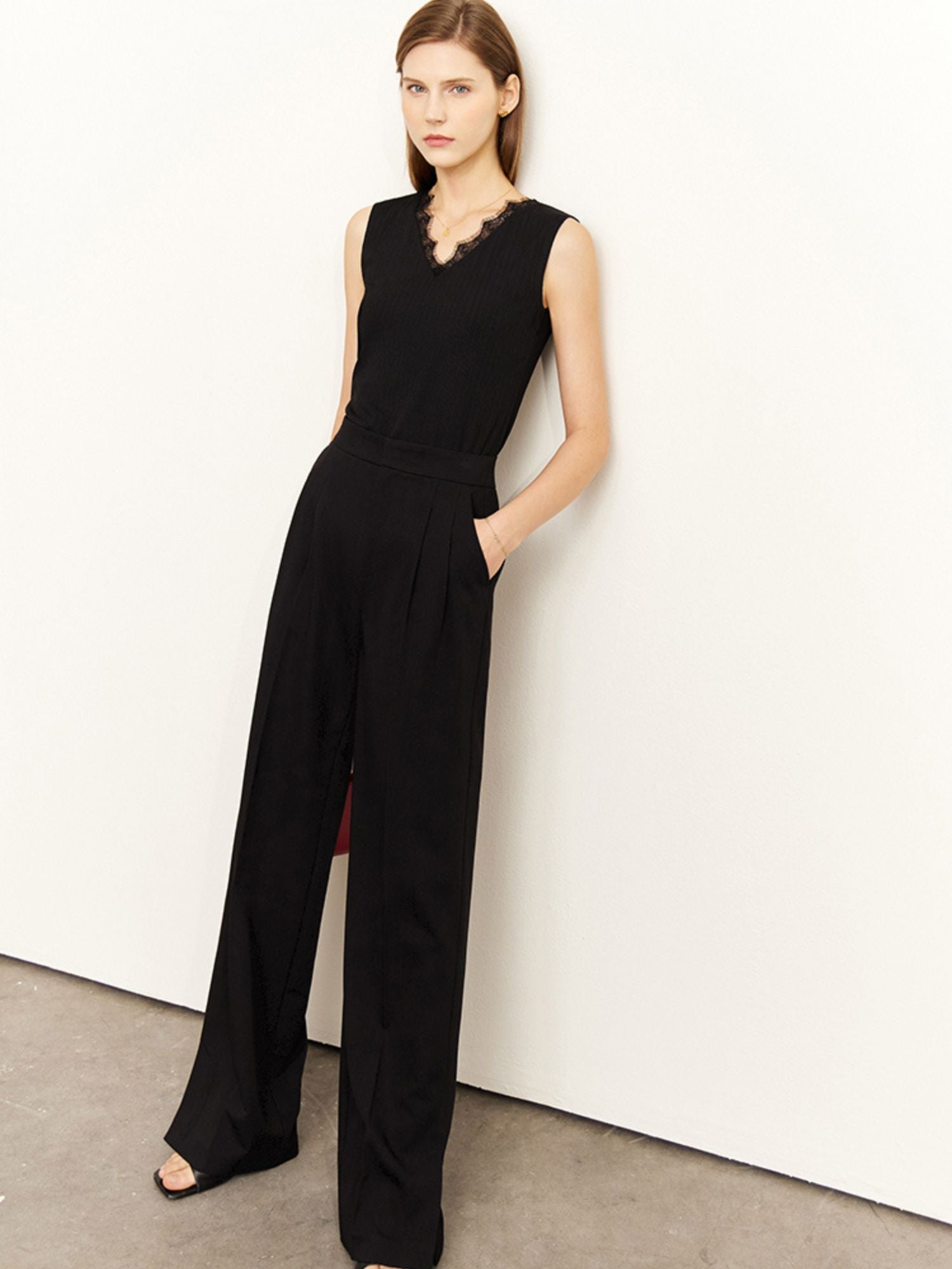 Frau steht in schwarzem ärmellosen Top mit weitem Bein, leicht von der Seite