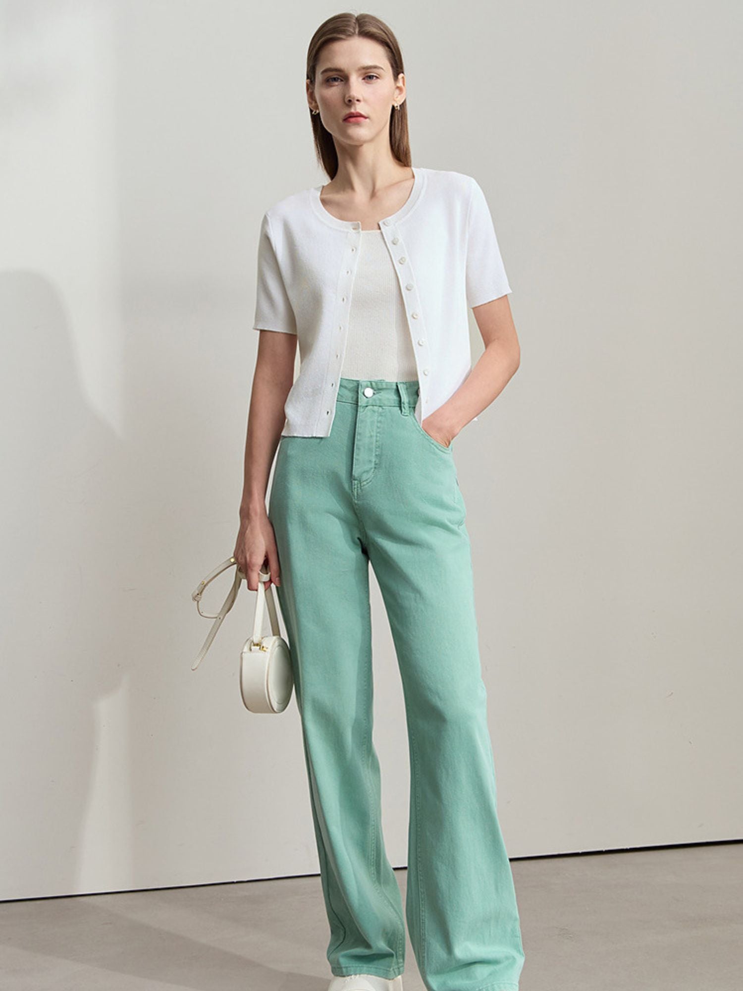 Frau trägt schwarzes Top mit kurzen Ärmeln und hellblauer Hose, frontal fotografiert