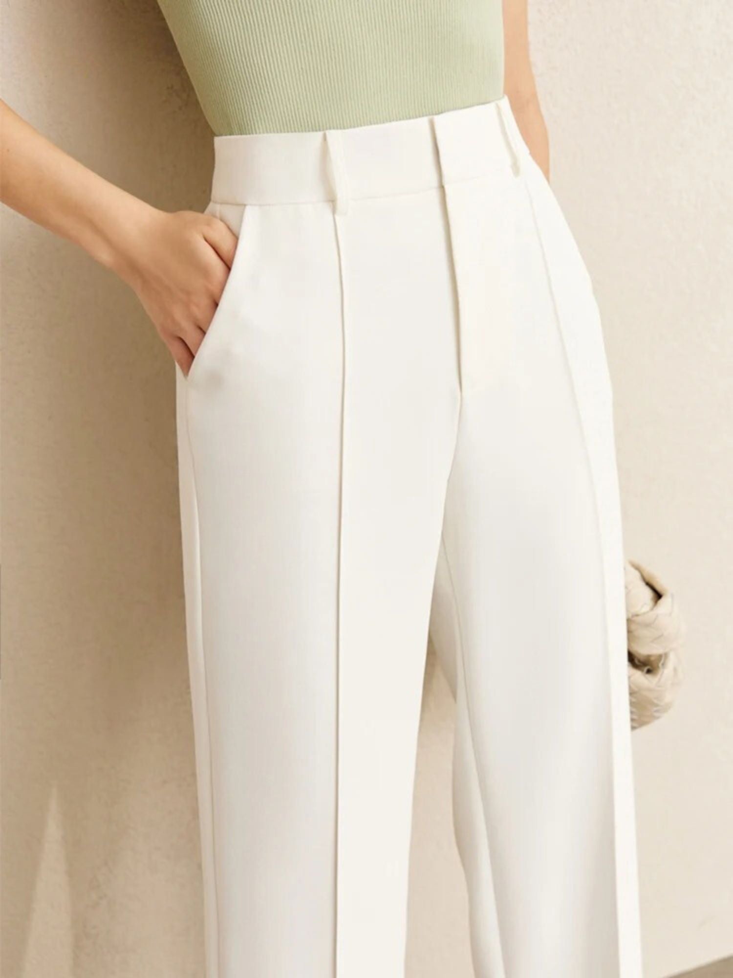 High-waisted white trousers with pleated front, styled with green ribbed top
